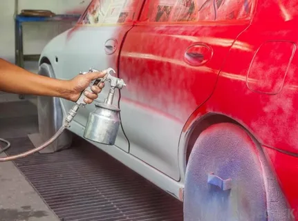 Professional car paint repair process showing red paint spray application on car body